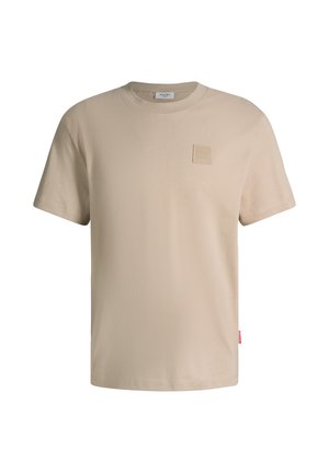 Beige T-Shirt mit kurzen Ärmeln und Rundhalsausschnitt, mit kleinem quadratischem Logoaufnäher auf der linken Brust und rotem Etikett an der linken Seitennaht.