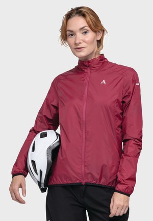 Maroon lightweight cycling jacket with zip front, high collar, and elastic cuffs, held with a white helmet against a neutral background.