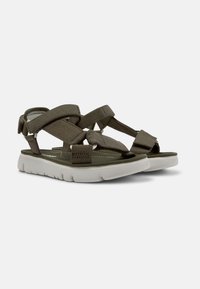 Gröna tygsandaler med flera justerbara remmar, vit vadderad sula och texturerad fotbädd för bättre grepp.