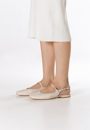 Beżowe skórzane buty na obcasie typu slingback z okrągłym noskiem, paskiem na kostce i małym blokowym obcasem, umieszczone na neutralnym tle.