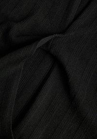 Gros plan d’un tissu côtelé noir doux torsadé pour montrer la texture et le motif tricoté.