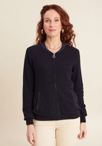 Cardigan zip-up navy in maglia testurizzata con scollatura rotonda, due tasche e polsini e orlo a coste. Sottili accenti brillanti sul colletto.