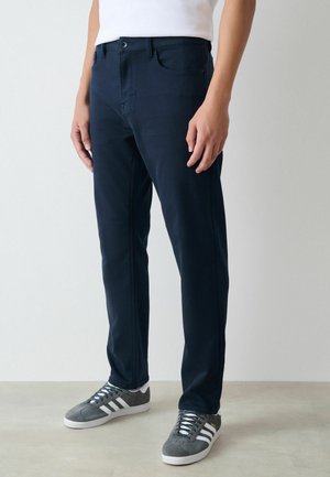 Navy blue trousers with a slim fit. Made from cotton-blend fabric, featuring a standard button and zipper closure, five pockets, and belt loops.