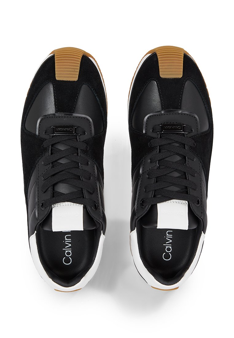 Sneaker nere in pelle e camoscio, con un accento bianco sulla linguetta, lacci neri e una suola in gomma con suola color gomma.