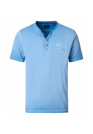 Hellblaues Henley-Shirt mit kurzen Ärmeln, drei Knöpfen und einem kleinen bedruckten Patch auf der linken Brust.