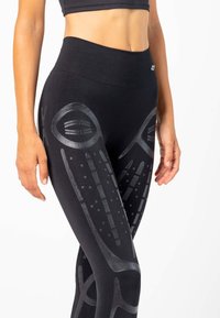 Zwarte leggings met reflecterende patronen en graphics. Hoog ingezette taille met een gladde textuur en een strakke pasvorm.
