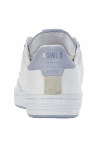Sneakers bianchi in pelle con un tallone in suede grigio, lati perforati e suola in gomma testurizzata. Presentano il marchio "K-Swiss" e l'anno 1966.