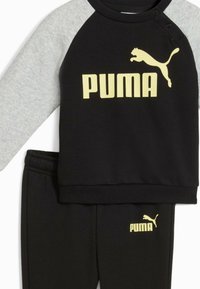 Mustat ja harmaat Puma-track suit, jossa on pyöreä pääntie, pitkät hihat ja joustava vyötärö. Yläosassa on rohkea keltainen logo ja yksityiskohtia.