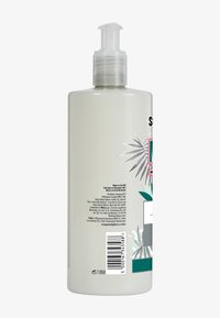 Bouteille de pompe en plastique transparent avec une couleur ivoire clair. Présente un design d'étiquette botanique, des accents verts et du texte imprimé. Contient des codes-barres au dos.