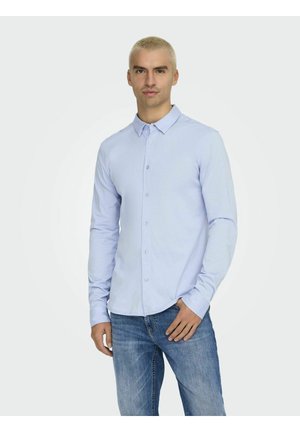 Hellblaues Langarmhemd mit Knopfleiste, glatte Stoffqualität, klassischer Kragen, vordere Knopfleiste. Kombiniert mit lässigen blauen Jeans.