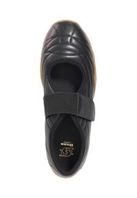 Black leather shoe with quilted texture, elastic strap across the instep, and a gum rubber sole. Rounded shape, designed for comfort.