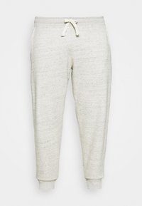 Pantalones de chándal gris claro hechos de una tela suave y texturizada. Cuentan con una cintura elástica con cordón y puños ajustados en los tobillos.