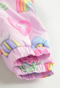 Veste de pluie colorée pour enfants en tissu lisse, dotée de motifs pastel comprenant des cœurs, des arc-en-ciel et des nuages ; poignets élastiques.