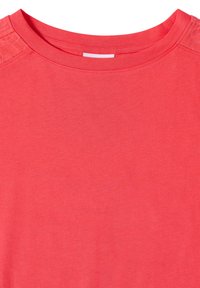 T-shirt rouge à col rond avec coutures simples et détail à motif subtil sur les épaules. Aucun logo visible ni motif supplémentaire.