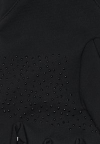 Svart tyg med ett strukturerat mönster av glänsande svarta nitar över ytan, med inslag av gathers på ena sidan.