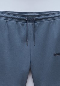 Gray sweatpants made of soft material, featuring an elastic waistband with drawstring, and a small black logo on the front.