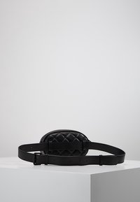 Bolso de cinturón de cuero negro acolchado con forma redondeada, correa ajustable y detalles de costura sutiles. Textura suave con mínimo hardware.