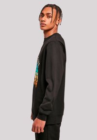 Schwarzer Sweatshirt mit einem bunten geometrischen Grafikdesign auf der Vorderseite, langen Ärmeln und Rundhalsausschnitt. Weicher Stoff und lässige Passform.