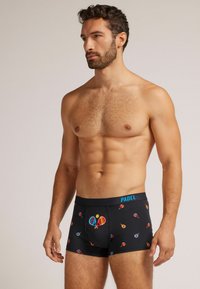 Boxers negros hechos de una tela suave que presentan diseños coloridos y estampados de palas y pelotas. Cinturilla elástica con "PADEL" en azul.