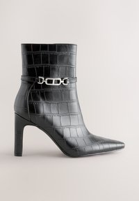 Black croc-embossed ankle boot with pointed toe, high heel, and silver chain detail across the front.