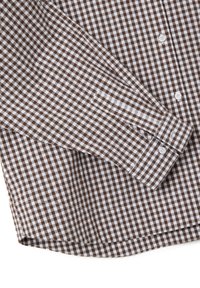 Camisa de manga larga con botones y un pequeño patrón de cuadros en marrón y blanco, mostrando claramente el puño y los botones delanteros.