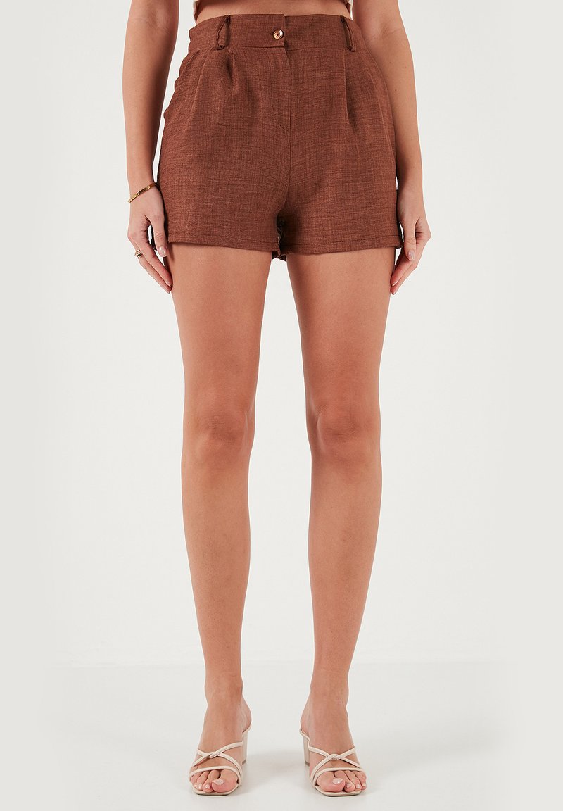 Shorts en mélange de lin marron à taille haute, dotés de plis sur le devant et d'une fermeture à bouton unique. Texture douce, coupe ajustée et design minimaliste.