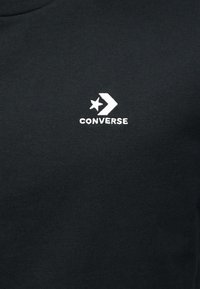 Μαύρο βαμβακερό φούτερ με λευκό κεντημένο λογότυπο "CONVERSE" και σχέδιο αστέρι και βέλος. Απλός, κλασικός σχεδιασμός χωρίς σχέδια.