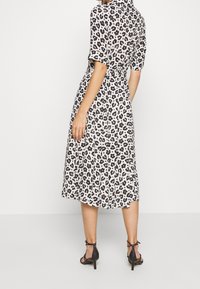 Midi šaty s leopardím potiskem v černé a krémové barvě, se krátkými rukávy, střiženým pasem a splývavou sukní. Nalezeno s černými lodičkami na kotníkovém pásku.