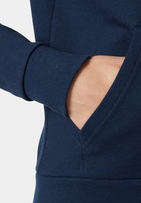 Sudadera azul marino con tejido suave, puños acanalados y un bolsillo frontal con apertura lateral para colocar las manos.