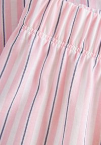 Lättviktig bomullstyg med vertikala ränder i rosa och vitt, med mörkblå accenter. Elastisk midja ger flexibilitet.