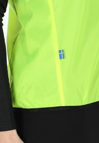 Jaszcze fluorescencyjnie żółte z odblaskowymi akcentami i niebieską flagą szwedzką. Posiada czarną warstwę podstawową i dopasowany krój.