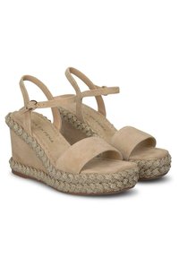Sandalias de cuña de ante beige con suela de esparto trenzada y acento dorado, y correas ajustables en el tobillo. Diseño de punta abierta.