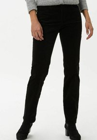 Black corduroy trousers with a straight-leg design, featuring front pockets and a textured surface. Matched with black heeled ankle boots.