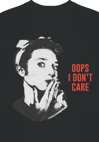 T-shirt nera in cotone con una grafica ad alto contrasto di una donna che fa il gesto di far silenzio e la scritta "OOPS I DON'T CARE" in rosso acceso e in grassetto.
