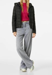 Černá péřová bunda s kapucí, prošívaný design. Fuchsie žebrovaný svetr pod tím. Světle šedé široké džíny a multibarevné tenisky.