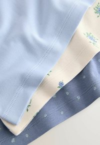 Drei Baumwoll-T-Shirts: hellblau, cremefarben mit floralem Muster und dunkelblau. Sie zeichnen sich durch eine weiche Textur und saubere Nähte entlang der Säume aus.
