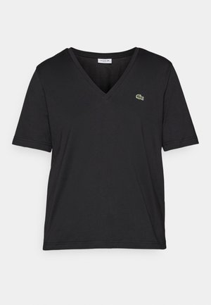Sort t-skjorte med kort erm og v-halsdesign, laget av mykt materiale. Har en liten grønn Lacoste-logo på venstre bryst.