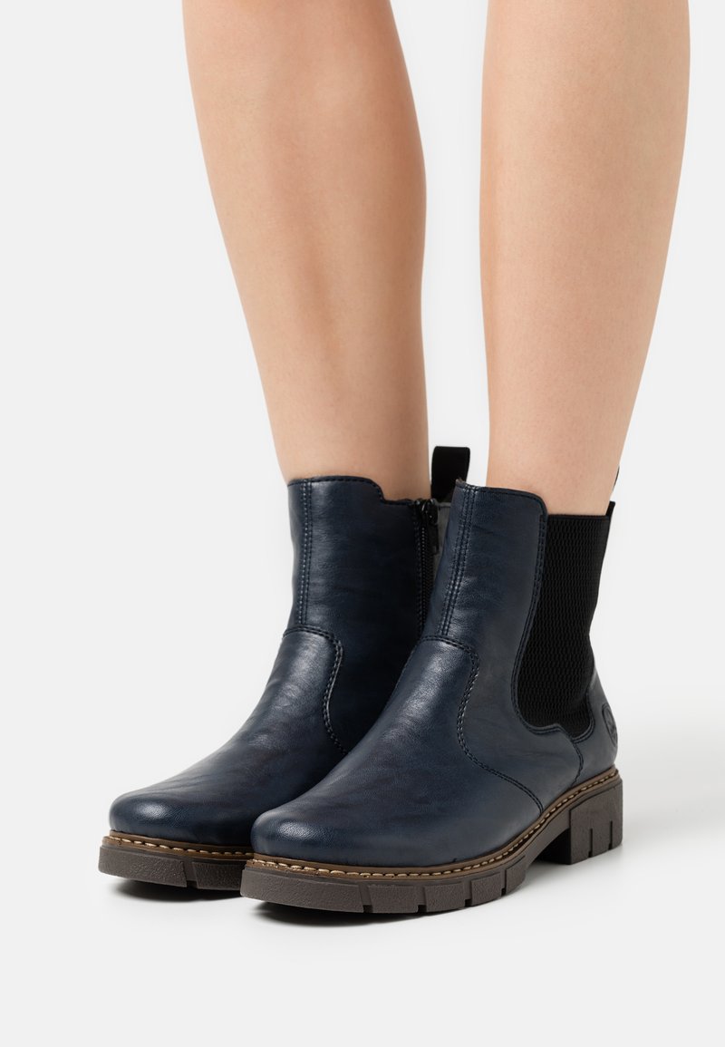 Bottines en cuir bleu marine avec des panneaux latéraux élastiques, une finition texturée et une semelle en caoutchouc épaisse avec une couture d'accent marron.