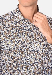 Camicia bianca a fiori con un motivo multicolore di fiori blu navy, marroni e gialli; colletto button-down; tessuto morbido.