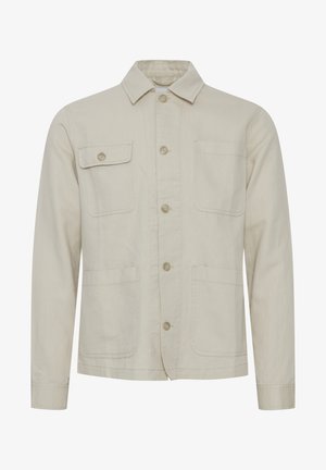 Bež puuvillane jakk, millel on nööbiga esikülg, terava kaelusega, kaks rinna-taskut ja kaks alumist taskut. Tekstuuriga kangas koos nähtava õmblusega.