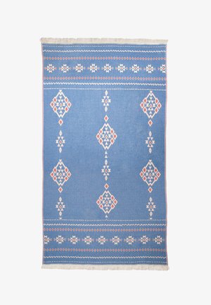 Blauwe geweven tapijt met diamanten patronen in wit en rood, met franjes langs één rand. Geometrisch ontwerp en gestructureerde afwerking.