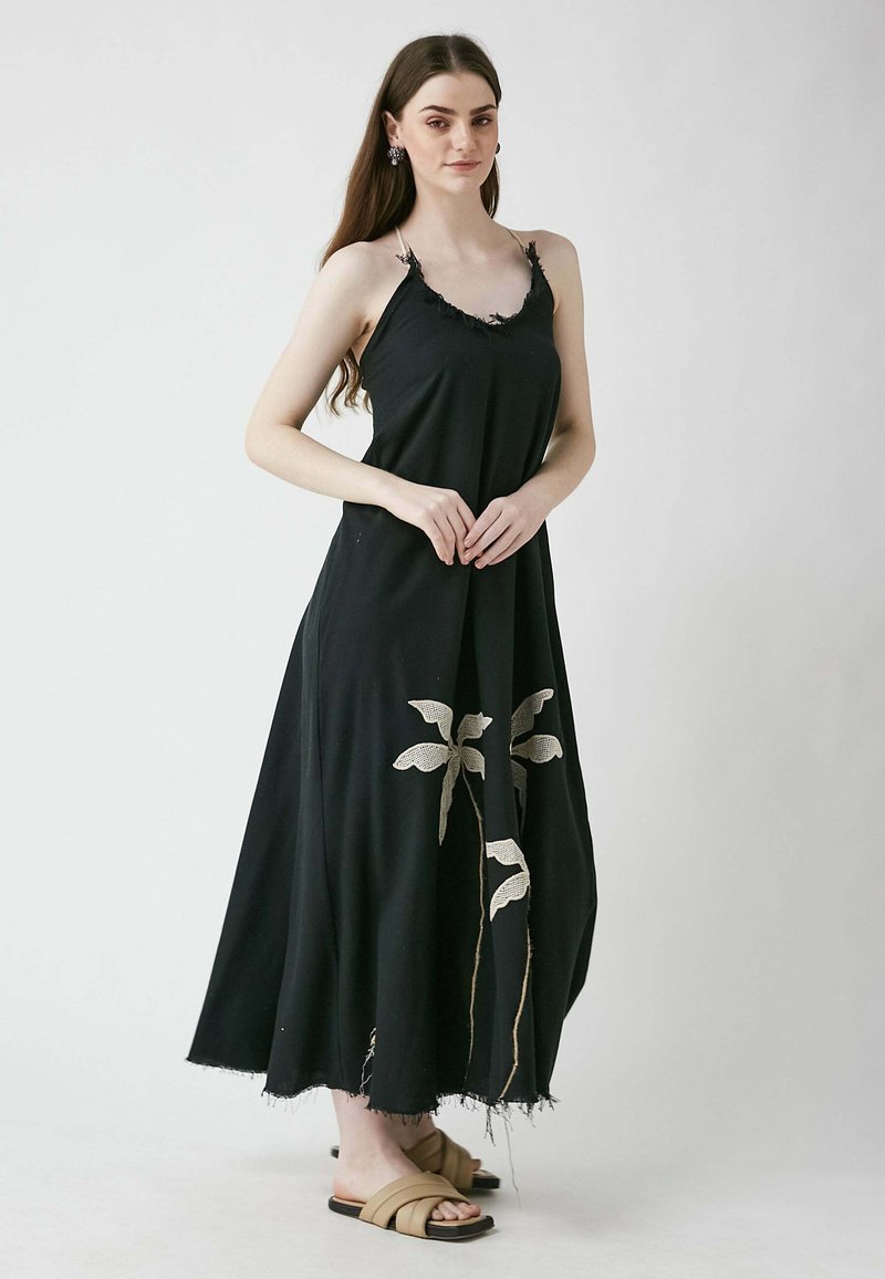 Schwarzes Maxikleid mit fransenbesetztem Ausschnitt und blattähnlichen Spitzenmustern. Hergestellt aus leichtem Stoff, zeichnet es sich durch eine fließende Silhouette und einen ausgefransten Saum aus.