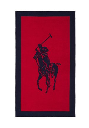 Tapis rectangulaire rouge avec une bordure noire présentant une silhouette noire d'un joueur de polo à cheval, brandissant un maillet.