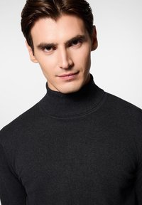 Czarny sweter z golfem w prążki o dopasowanym kroju, gładkiej teksturze i kołnierzu z paskiem. Zdjęcie z bliska podkreśla przeszycia oraz detale materiału.