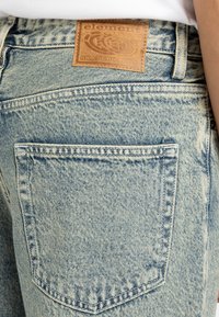 Lichtblauwe denim jeans met een gestructureerd oppervlak. Voorzien van een leren label met "element SKATEBOARDS" op de achterste taille. Eén achterzak zichtbaar.