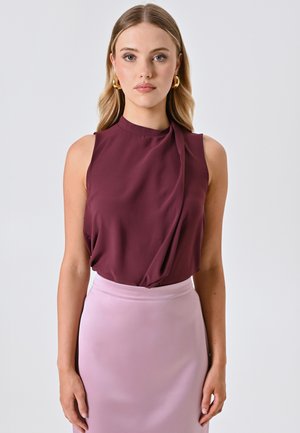 Burgundy sleeveless blouse with draped detail, paired with a smooth pastel pink pencil skirt. Fabric appears soft with a slight sheen.