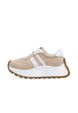 Béžový semišový teniska s bílými dvouvrstvými proužky po stranách, tlustou bílou podrážkou, hnědou strukturovanou podrážkou a bílými tkaničkami, zobrazená z boku.