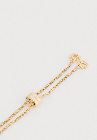 Pulseira de cordão dourado torcido com dois detalhes em forma de sol, apresentando um fecho cilíndrico liso com texto gravado e acabamento polido.