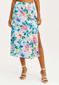 Květinová maxi sukně z měkké, lehké tkaniny s světle modrým pozadím, zdobená barevnými květinami a vysokým bočním rozparkem.