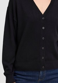 Cardigan lavorato a maglia nero con scollo a V, dotato di sette bottoni neri sul davanti e polsini e orlo a coste.